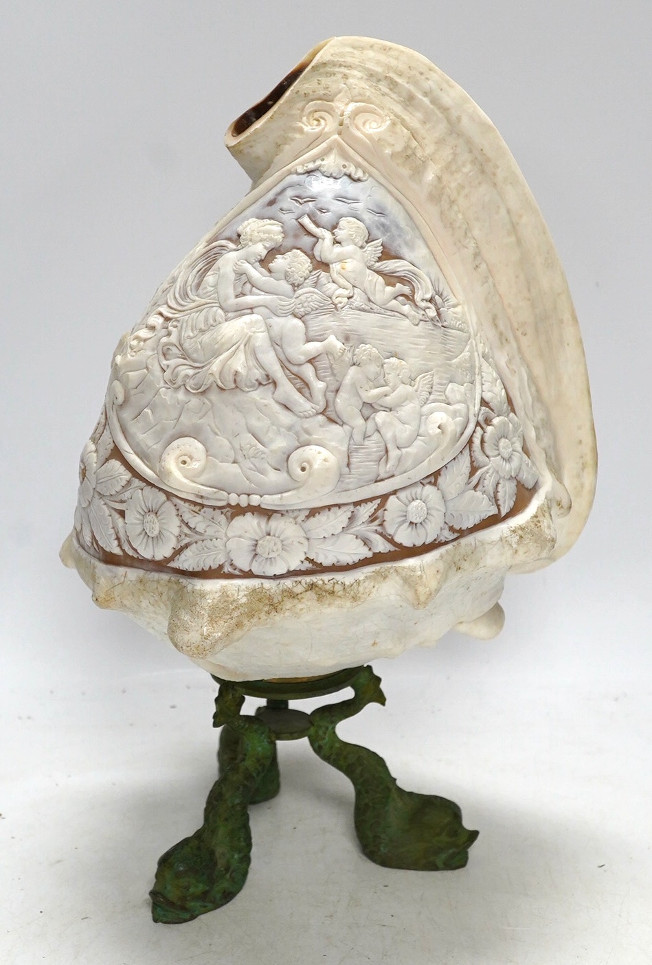 A late 19th/early 20th century large Neapolitan carved conch shell on bronze ‘dolphin’ base, height 29cm. Condition - fair, splinter chips to reverse